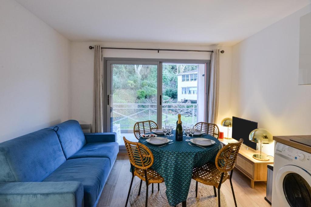 uma sala de estar com um sofá azul e uma mesa com cadeiras em Le Cyana em Cagnes-sur-Mer
