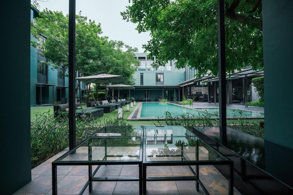A courtyard pool framed from a shaded glass-fronted seating area.
