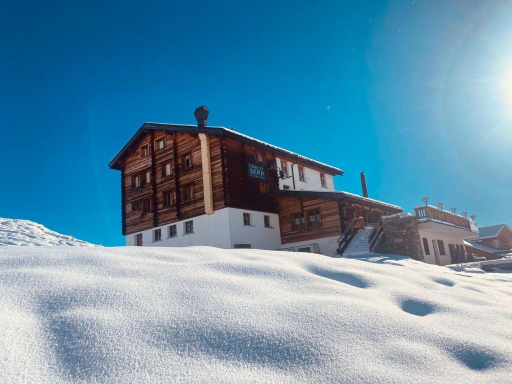 un grand bâtiment en bois dans la neige dans l'établissement Chalet Sepp, à Belalp