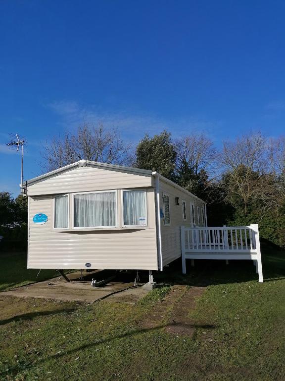 a tiny house with a porch and a bench at Yare Village, Breydon water holiday park in Great Yarmouth