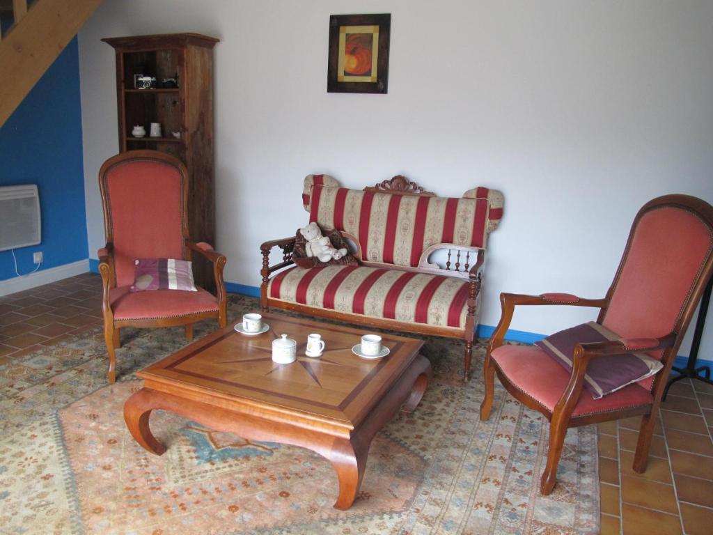uma sala de estar com um sofá e duas cadeiras em poppy chambres d'hotes em Tursac