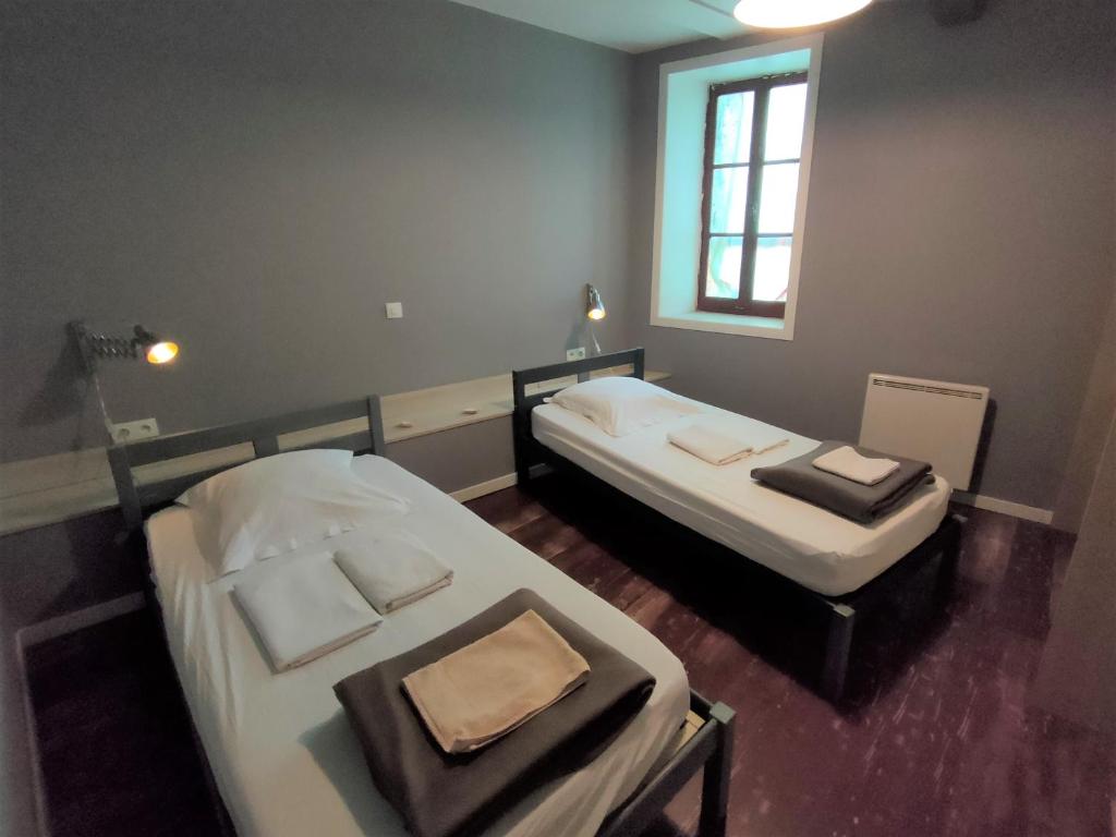 2 Betten in einem kleinen Zimmer mit Fenster in der Unterkunft Moissac - La coquille à deux pas de l'Abbaye in Moissac