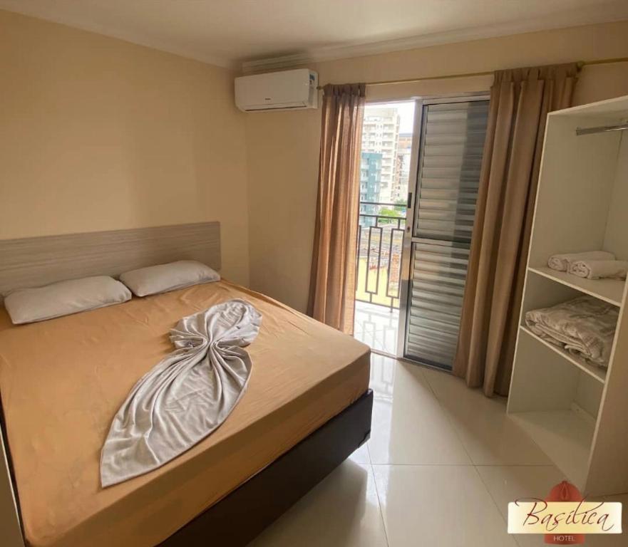 a bedroom with a bed and a large window at Basilica Palace Hotel in Aparecida