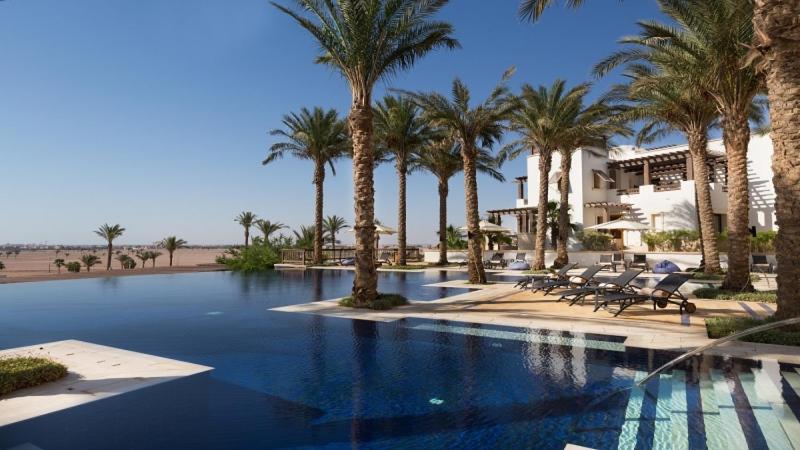 una piscina con palmeras y sillas junto a un edificio en El Gouna en Hurghada