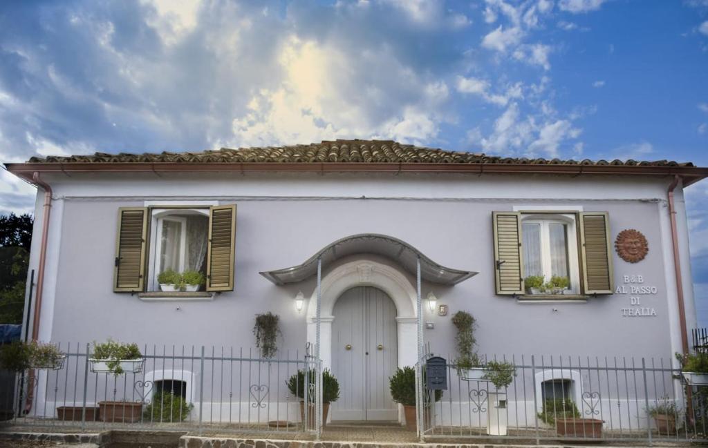 ein weißes Haus mit grünen Fensterläden und einer Tür in der Unterkunft Al Passo di Thalia in Ricadi