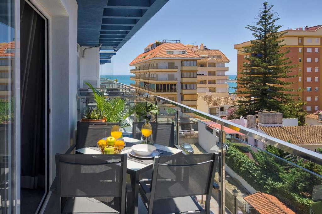 balcón con mesa y sillas y vistas al océano en Sur Suites La Dorada en Fuengirola