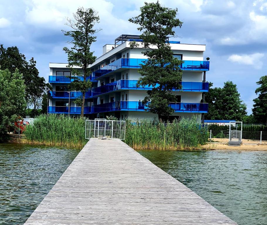 a building with a dock next to a body of water at Apartamenty Boszkowo Aquarius Blue in Boszkowo
