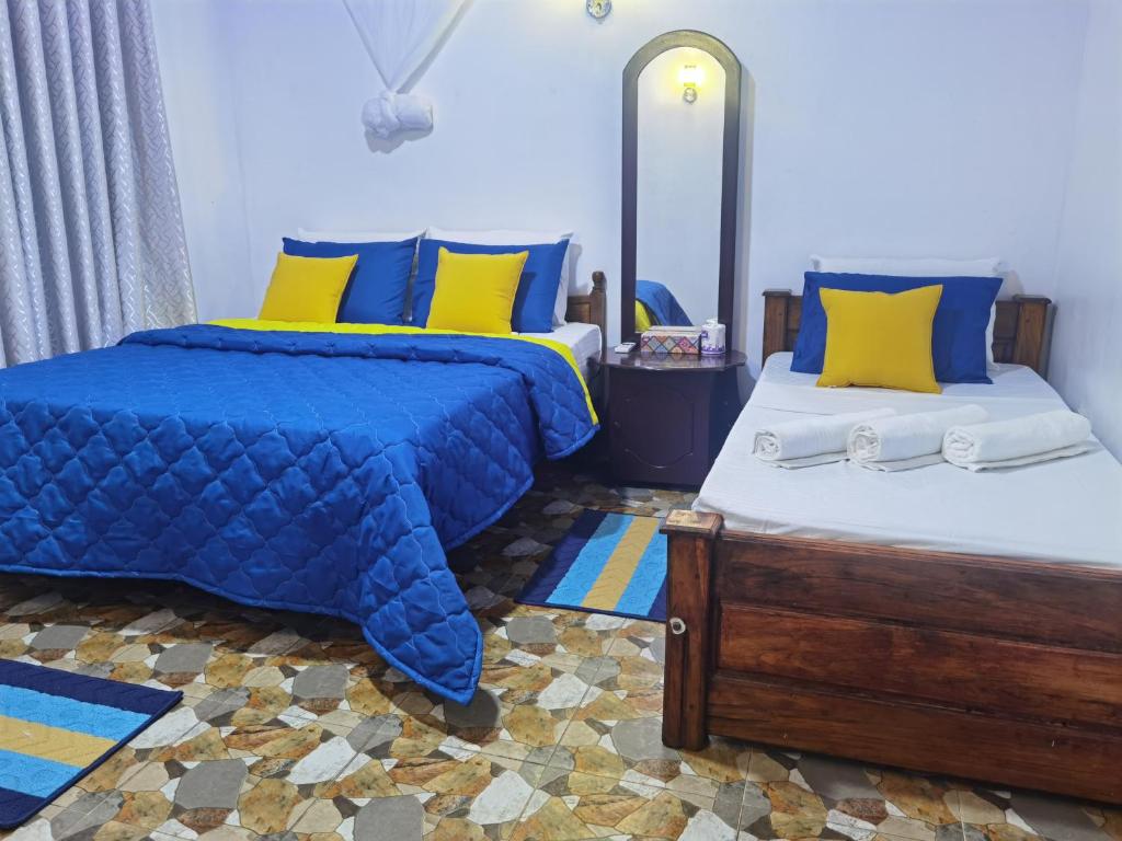 a bedroom with two beds with blue and yellow pillows at City Paradise Dambulla in Dambulla