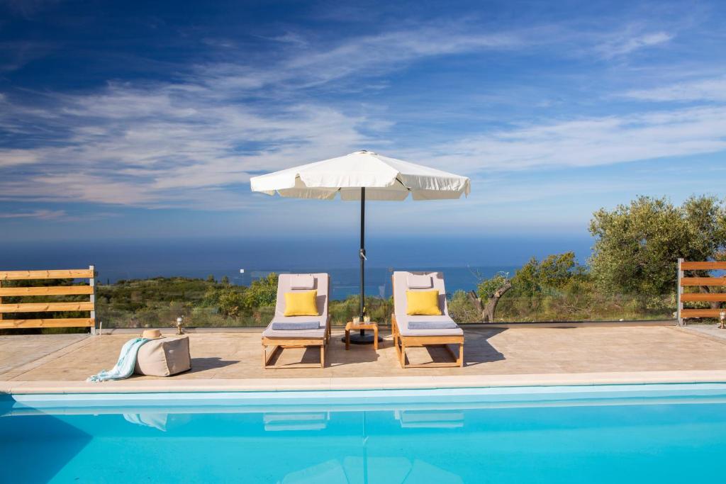 twee stoelen en een parasol naast een zwembad bij Villa Freya in Kalamitsi