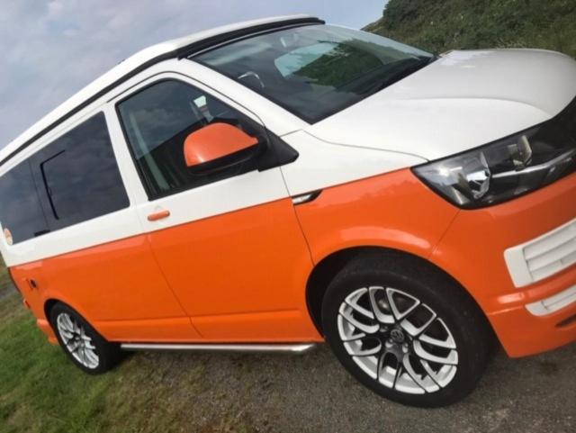 Kirk Braddon的住宿－Campervan and Motorhome Hire Isle of Man，停放在田野上的橙色和白色汽车