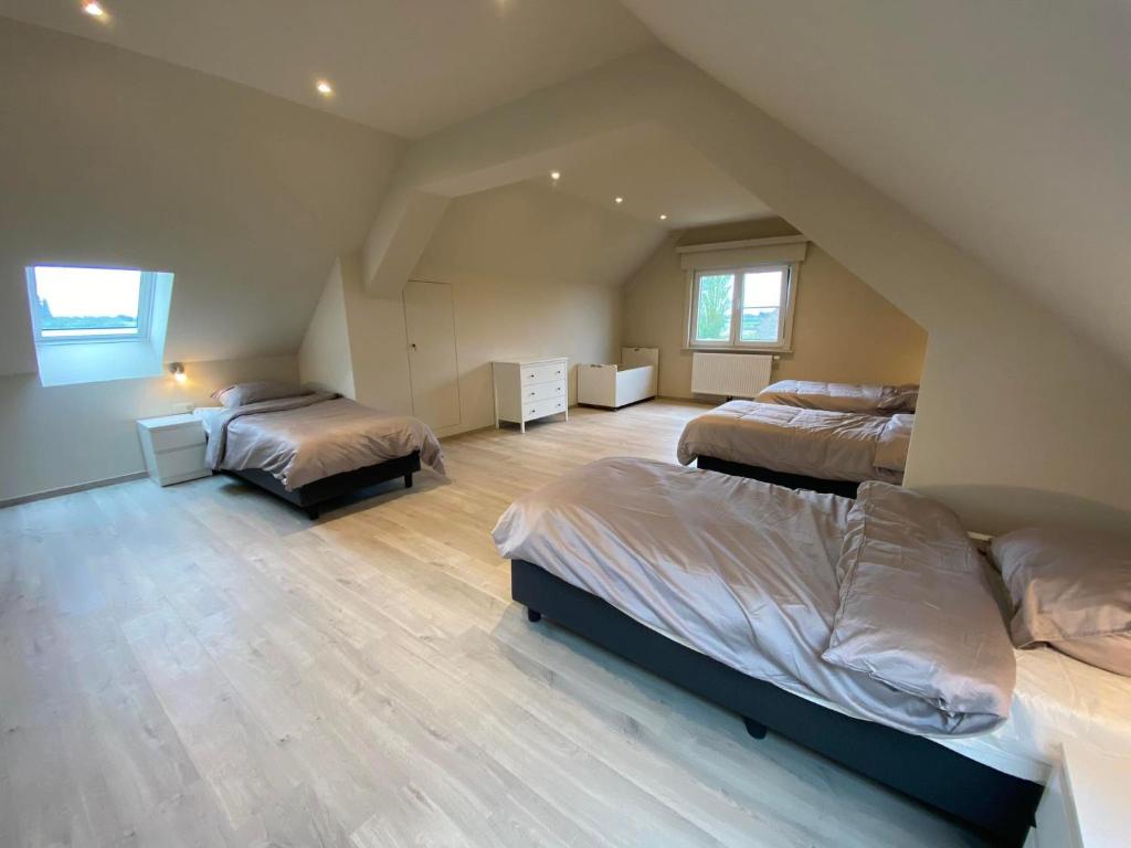een slaapkamer op zolder met 2 bedden en houten vloeren bij 't Cappellelandhof in Lo-Reninge