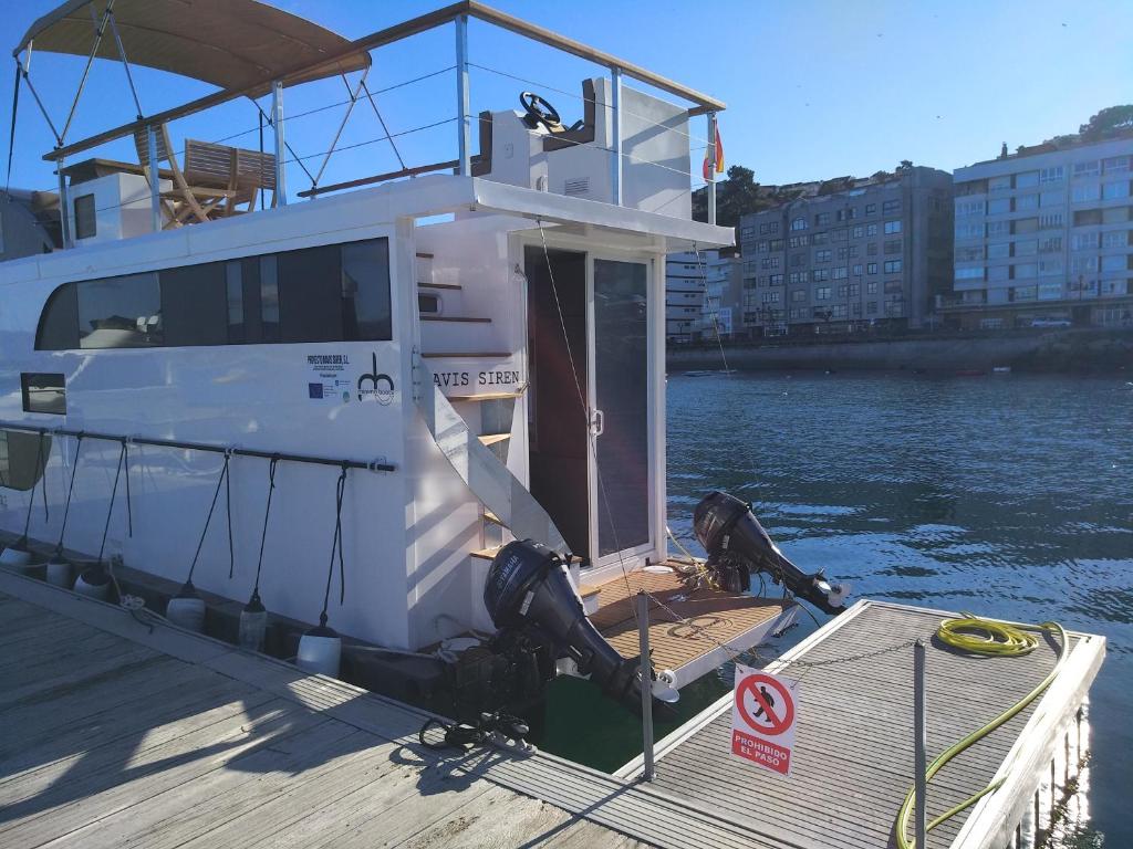 a boat is docked at a dock in the water at NAVIS SIREN Barco Apartamento in Baiona