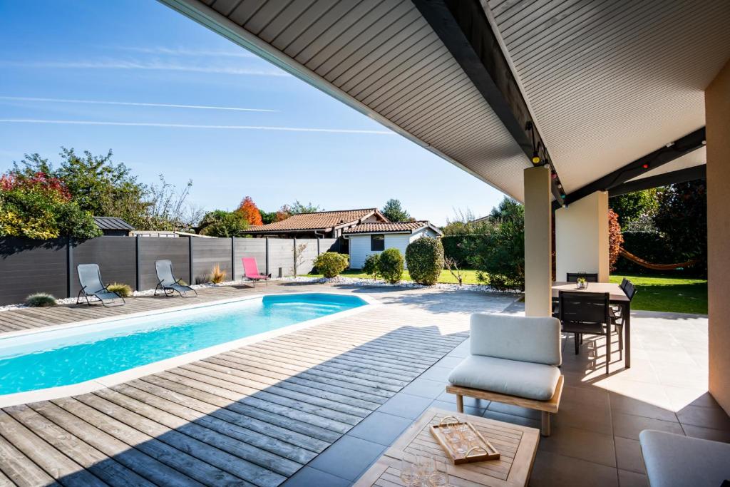 a patio with a pool and a chair and a table at Frenchyhomes☆villapiscine☆8pers☆centrebassin in Biganos