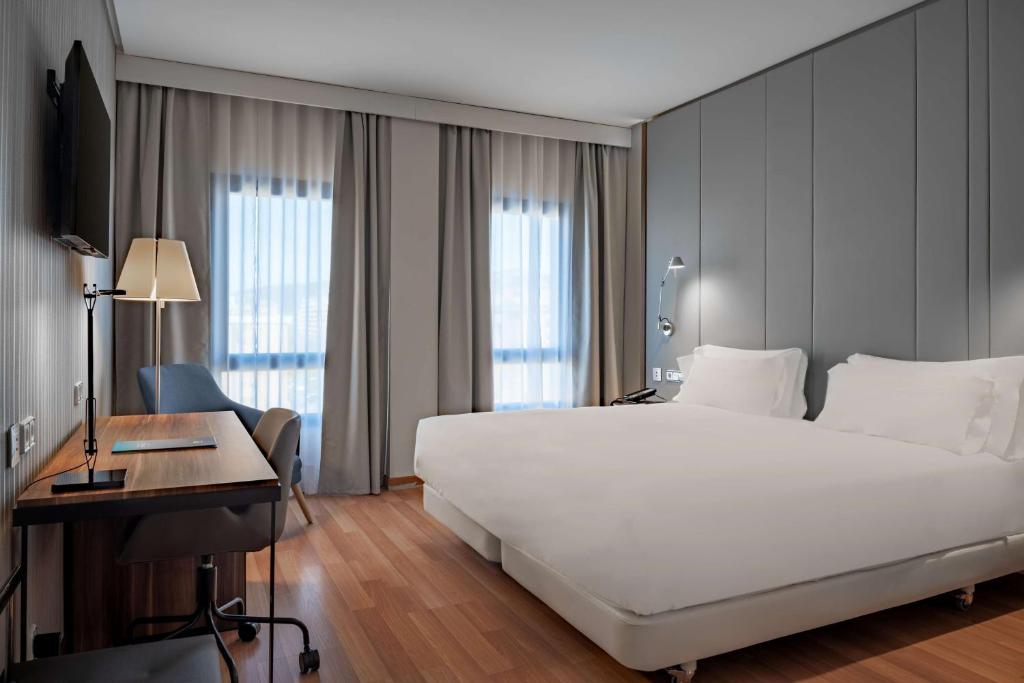昆卡的住宿－NH昆卡城市酒店，卧室配有一张白色大床和一张书桌