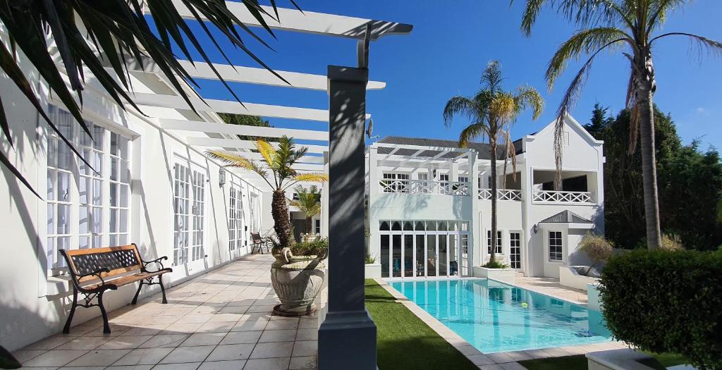 a white house with a swimming pool and palm trees at Die Kasteel, Belvidere Estate in Knysna