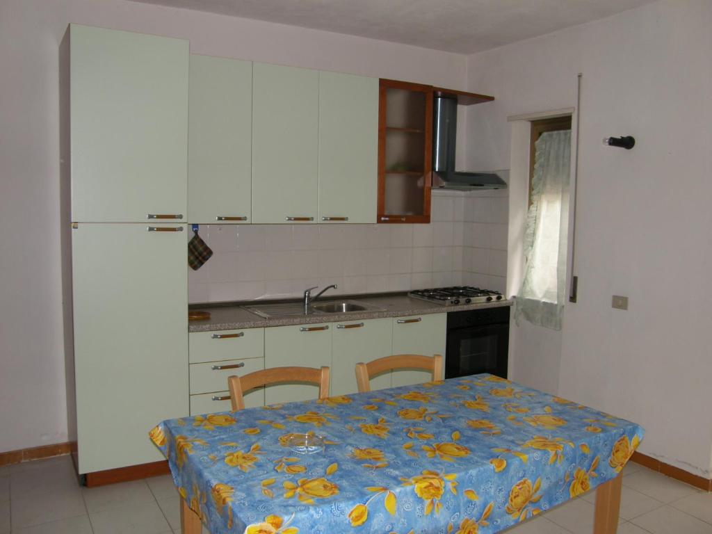 a kitchen with a table with a blue table cloth on it at Isola Rossa Appartamenti Standard in Isola Rossa