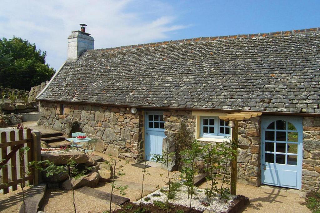 une maison en pierre avec des portes bleues et une clôture dans l'établissement Stone House in Brittany with Sea Views, à Plougasnou