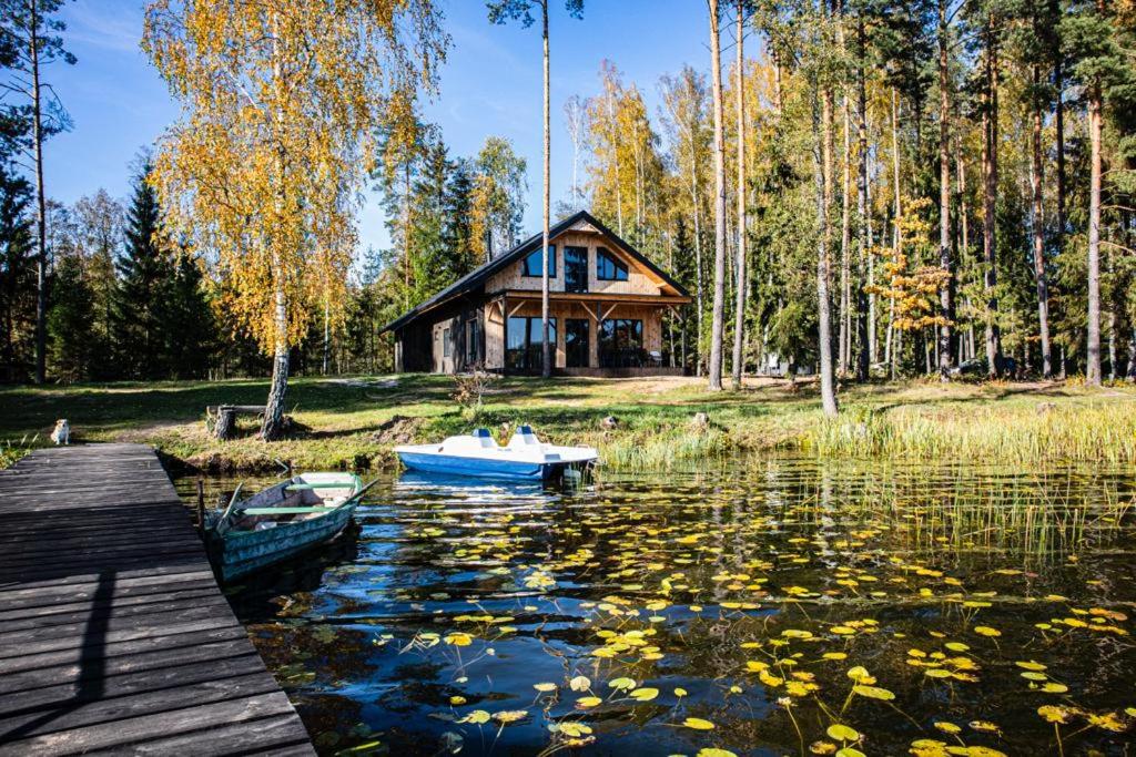 una casa en un lago con un barco en el agua en Duni en Kalvāni