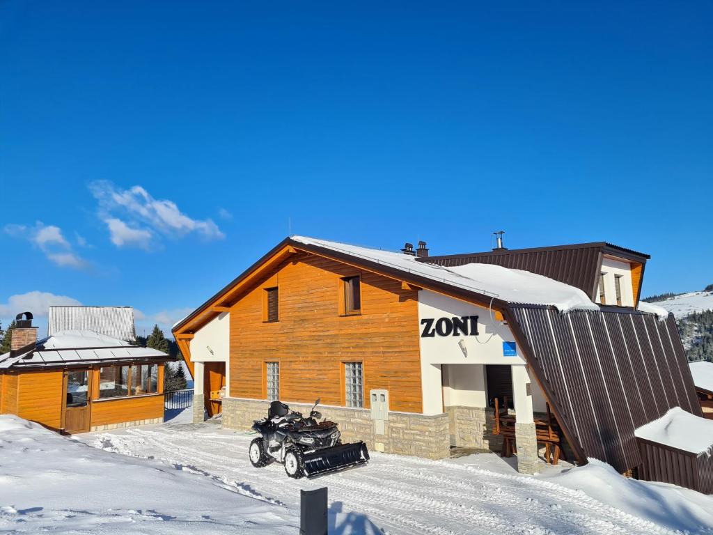 a motorcycle parked in the snow in front of a building at Apartments Zoni in Vlasic