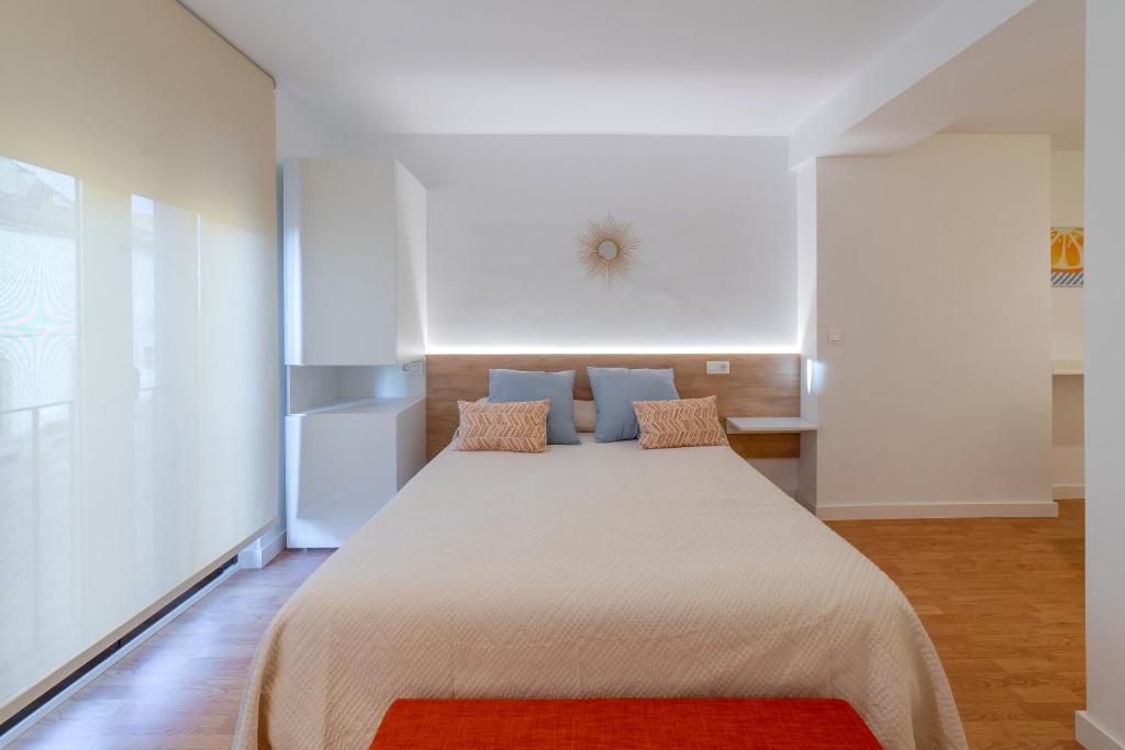 a bedroom with a large white bed with a red rug at Apartamentos Turísticos Torres De Santiago in Úbeda