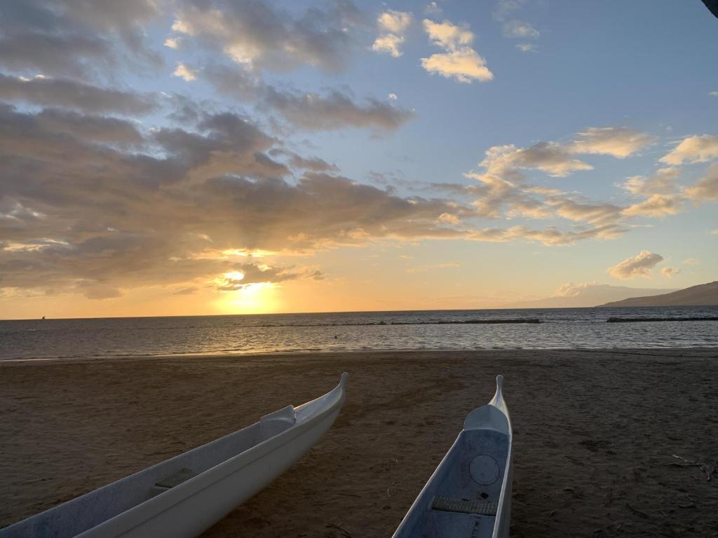 two boats sitting on the beach with the sunset at Kihei Bay Surf D142 A Safe Place To Stay in Kihei