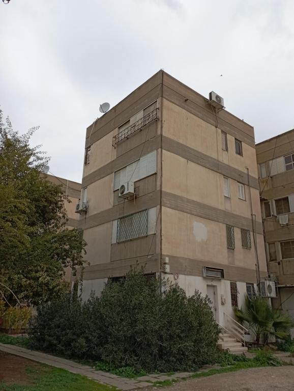 un edificio de talla con ventanas y arbustos delante de él en Casa de Yair, en Beer Sheva