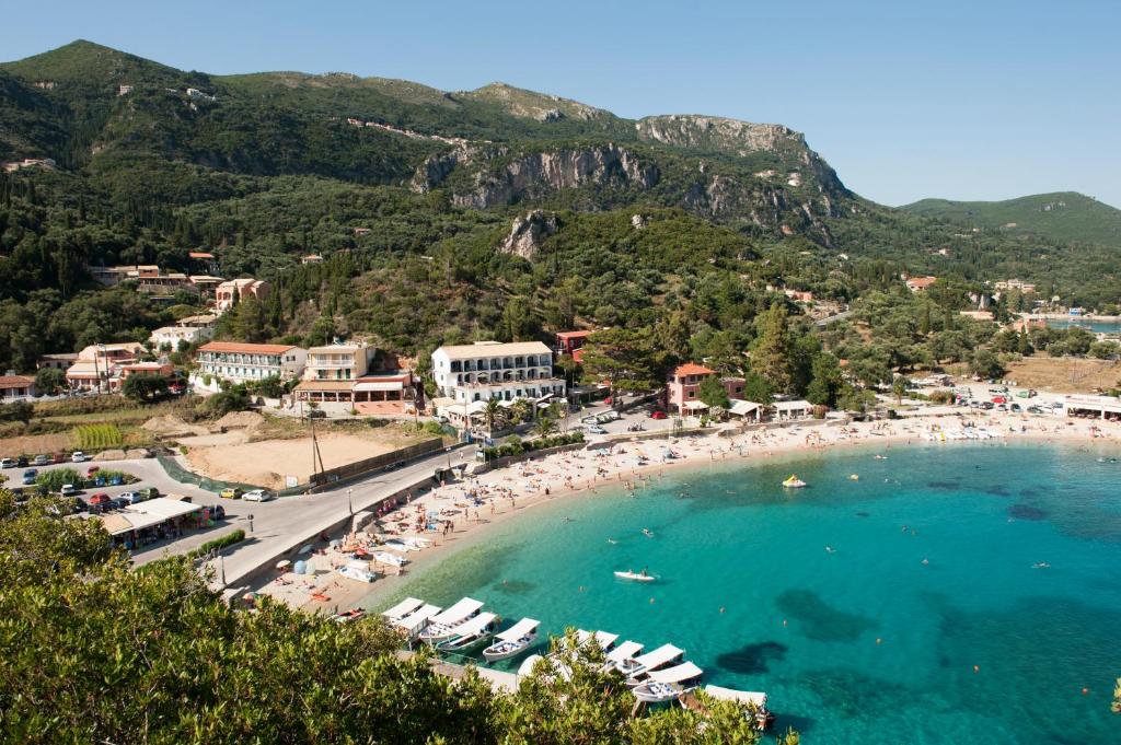 una playa con un montón de sombrillas y multitudes de personas en Hotel Apollon Corfu, en Paleokastritsa