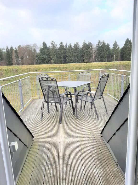 a patio with a table and chairs on a deck at "Libelle am Bernsteinsee" in Stüde, Sassenburg in Sassenburg