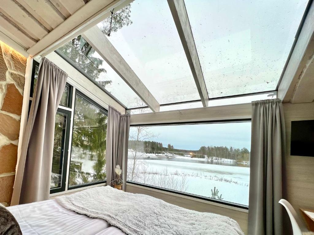 1 dormitorio con ventana grande y 1 cama en una habitación en Glass Igloos by the water - Lasisviitit, en Laukaa