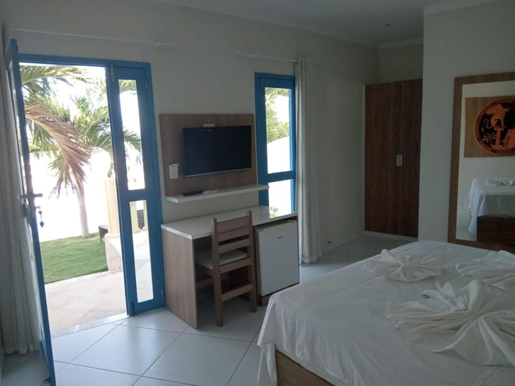 a bedroom with a bed and a desk and a television at Il Mondo Di Sofia in Canoa Quebrada
