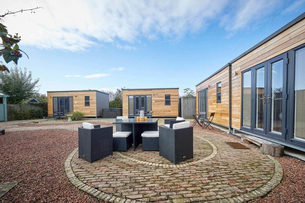 um pátio com uma mesa e cadeiras em frente a uma casa em Goldenhill Retreats em Bamburgh