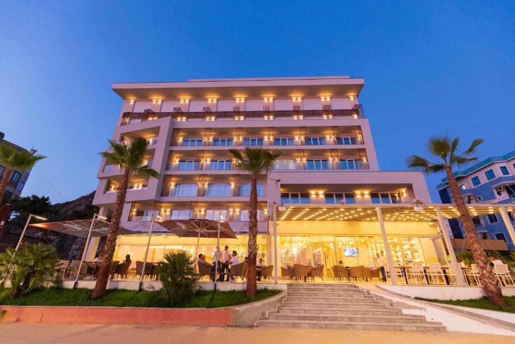 a hotel with palm trees in front of a building at AMR Hotel - Durres in Durrës