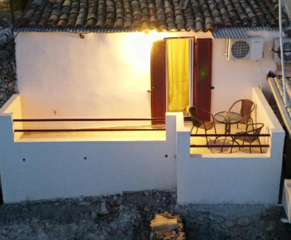 a small white house with a chair on the porch at Manto Apartments Lefkada in Évyiros