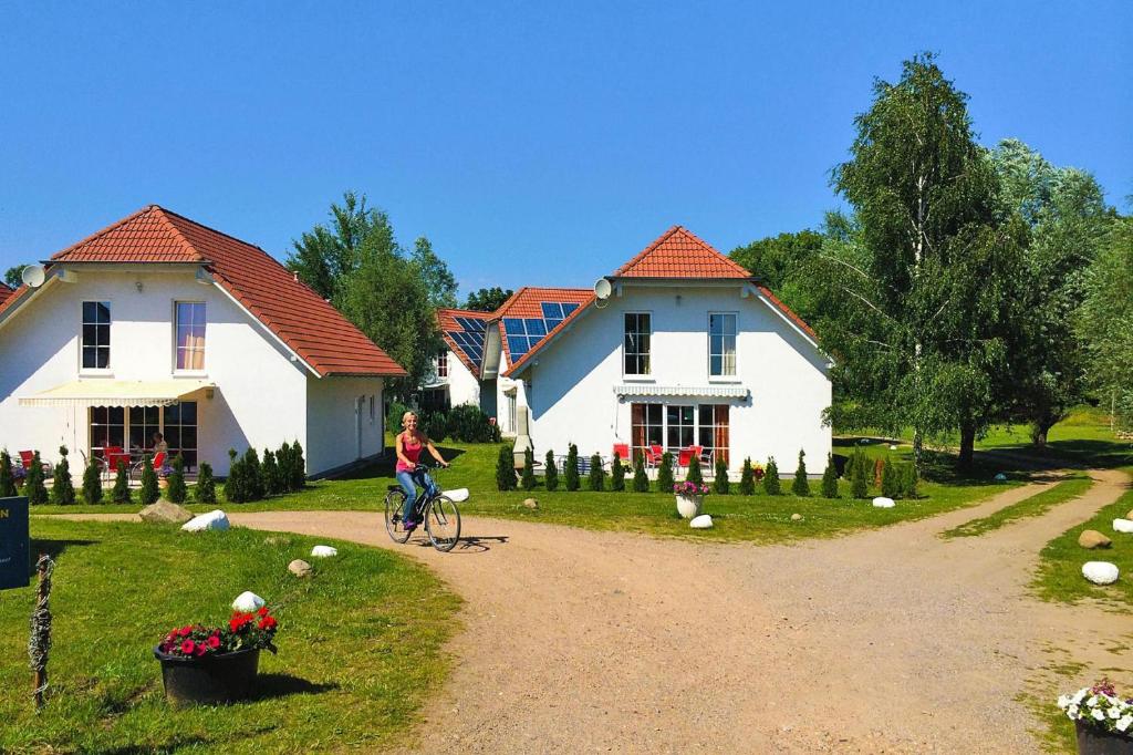 a person riding a bike in front of two houses at Cottages at the Kummerower See Verchen in Verchen