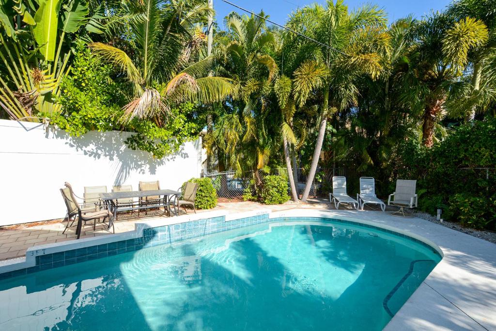 a swimming pool with chairs and a table and palm trees at Canal 313 - Right in Siesta Key Village! in Siesta Key