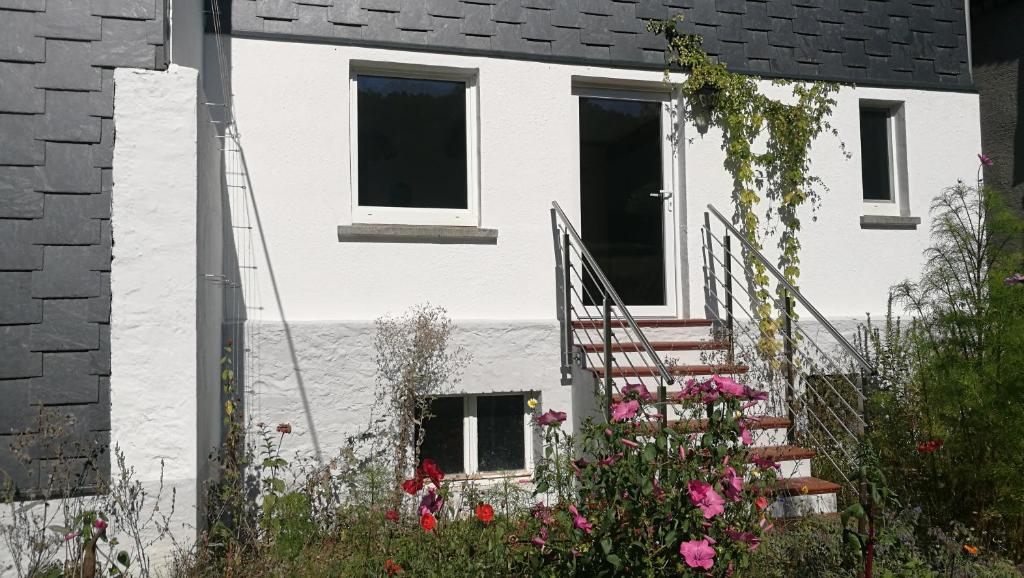 ein weißes Haus mit einer Treppe und Blumen in der Unterkunft Historisches Ferienhaus "Schwalbennest" mit Eseln in Holzhausen