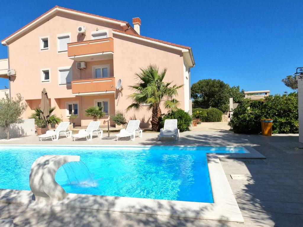 a villa with a swimming pool in front of a house at Apartments Zeneral in Novalja