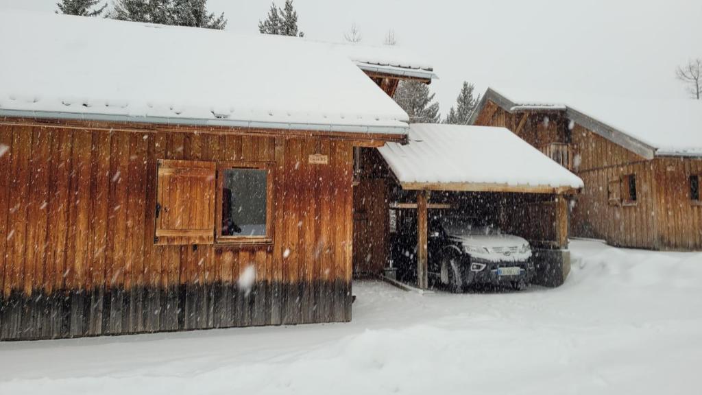 a car parked next to a building in the snow at Chalet By Sophie Superdevoluy avec piscine in Superdevoluy