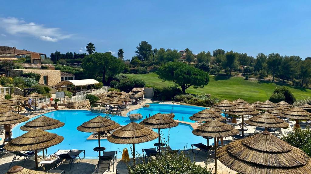 un complejo con un montón de sombrillas y una piscina en Hameau des amandiers-vue mer & golf, en Saint-Cyr-sur-Mer