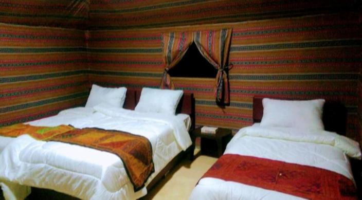 two beds in a room with striped walls at Moon city camp in Wadi Rum