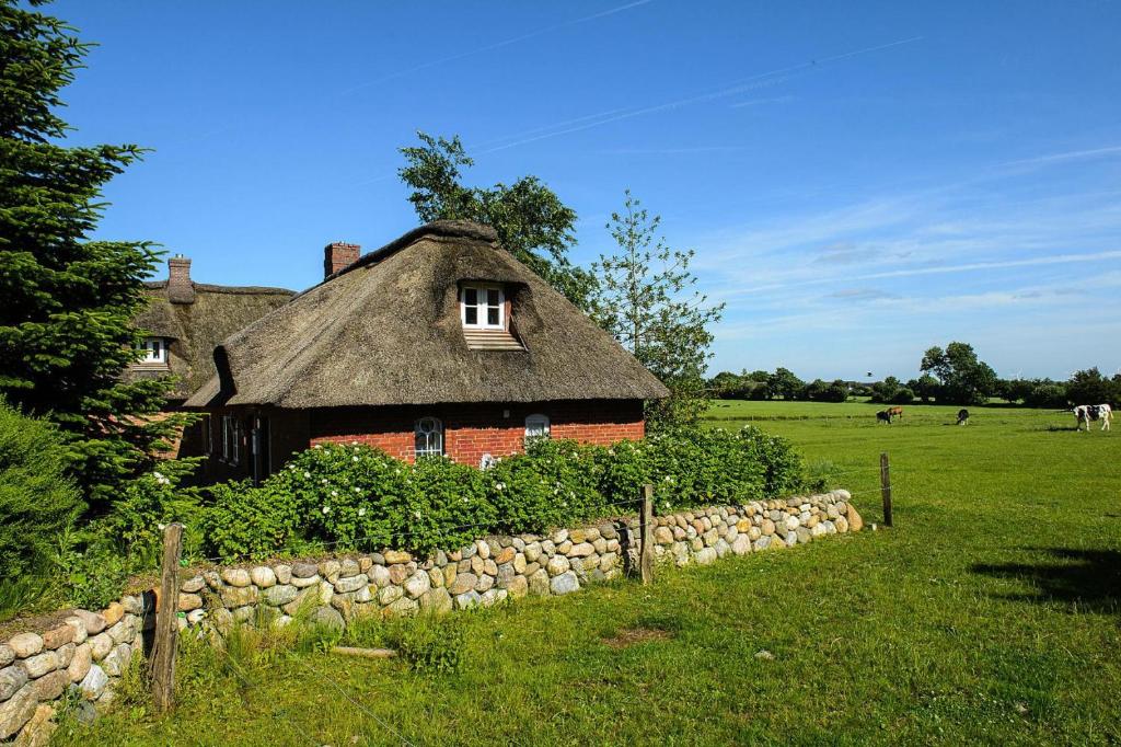 an old house with a thatched roof and a stone wall at Semi-detached house Posthus, Behrendorf in Behrendorf
