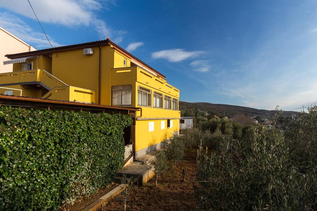 una casa amarilla con un seto delante de ella en The Manzoni family 5 en Punat