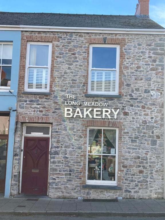 un edificio de ladrillo con un cartel de panadería. en Long Meadow Bakery en Pembrokeshire