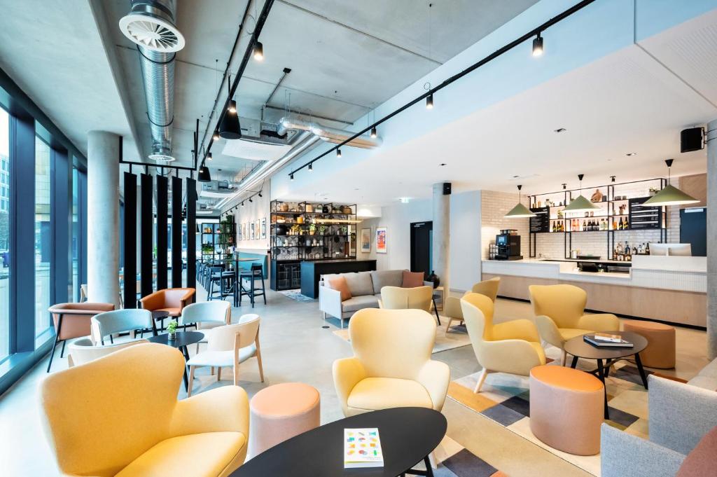 a lobby with chairs and tables and a bar at Staycity Aparthotels Frankfurt Airport in Frankfurt/Main
