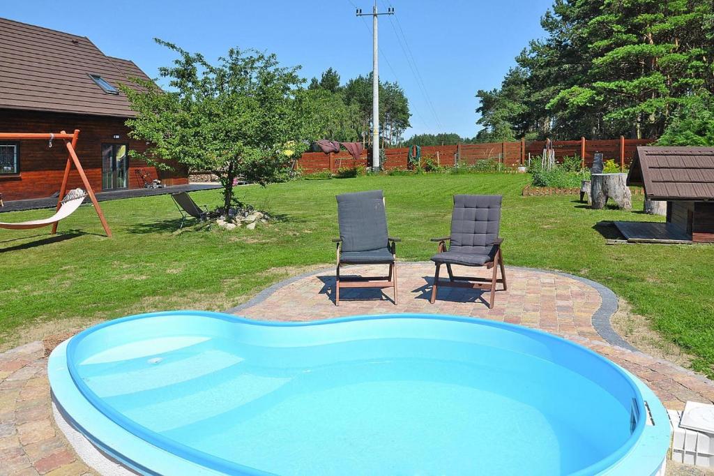 a swimming pool with two chairs and a swing at Holiday homes, Kolczewo in Kołczewo