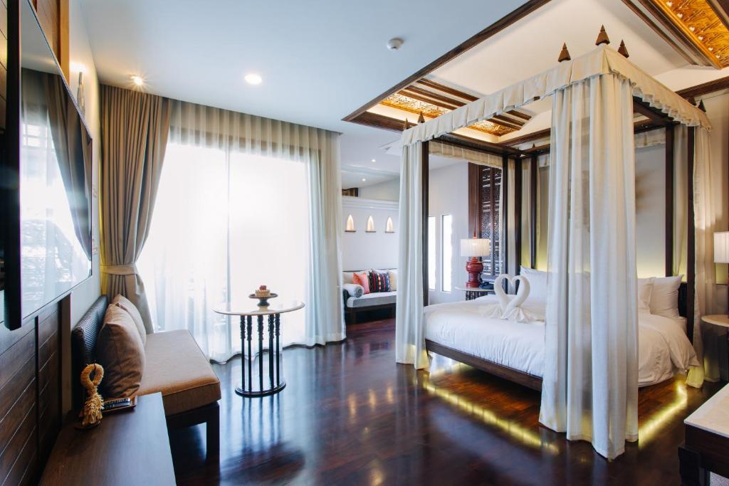 a bedroom with a canopy bed and a living room at T Heritage Hotel in Chiang Mai