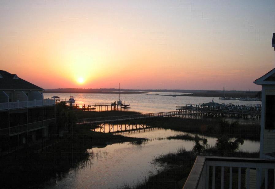 a sunset over a body of water with a dock at 113 Waters Edge Community in Folly Beach