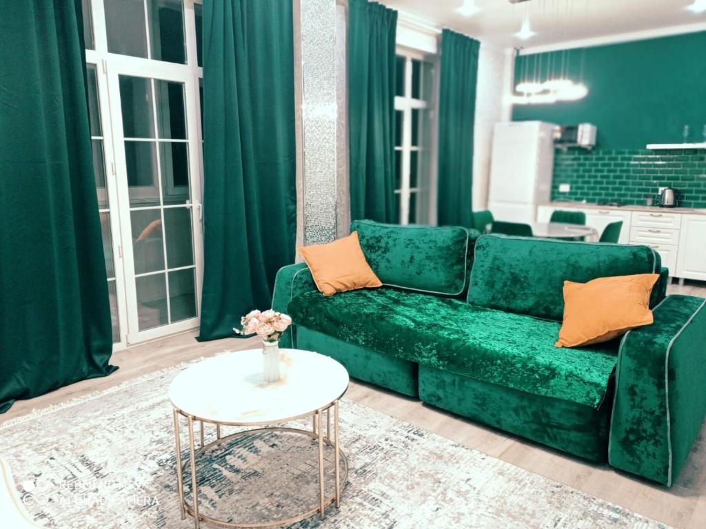 a living room with a green couch and a table at Large Green Apartment in Oral