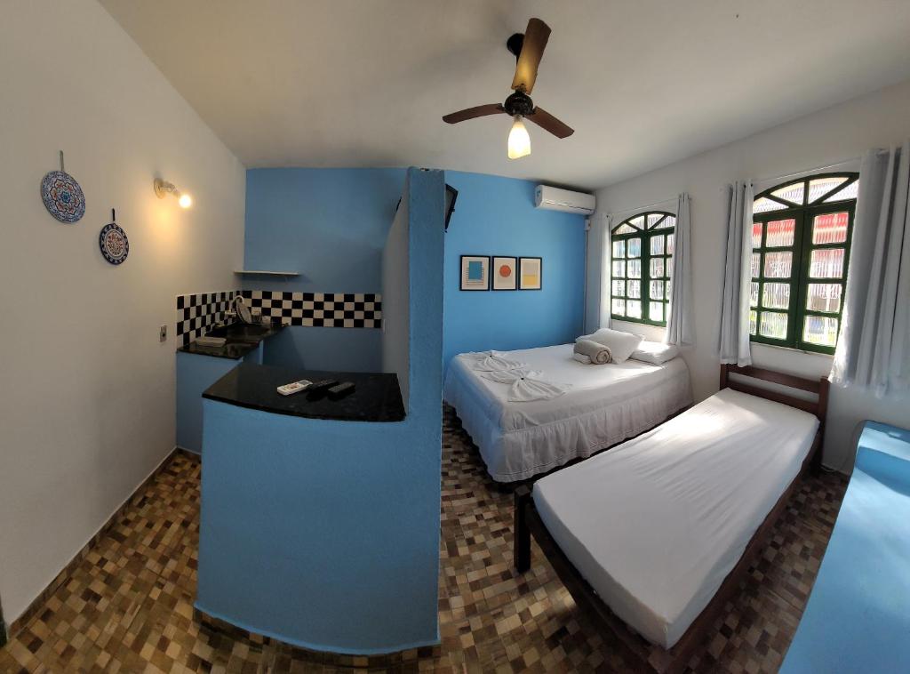 1 dormitorio con 2 camas y pared azul en Pousada Simbiose, en Arraial d'Ajuda