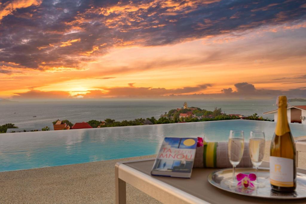 a table with a bottle of wine and glasses next to a pool at Michael villa in Koh Samui